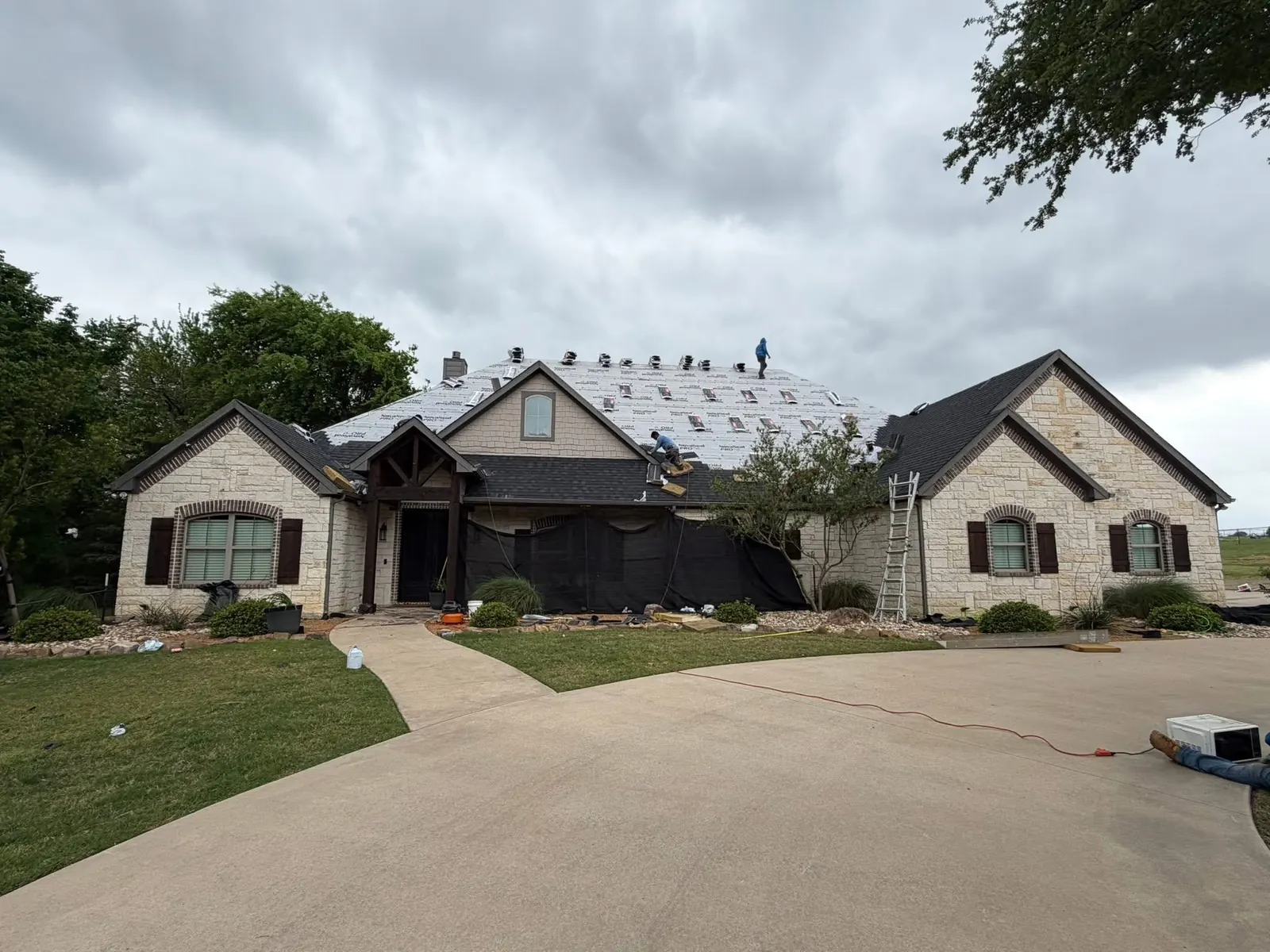 A Bridges Roofing crew tearing off and re-decking a stone home's roof